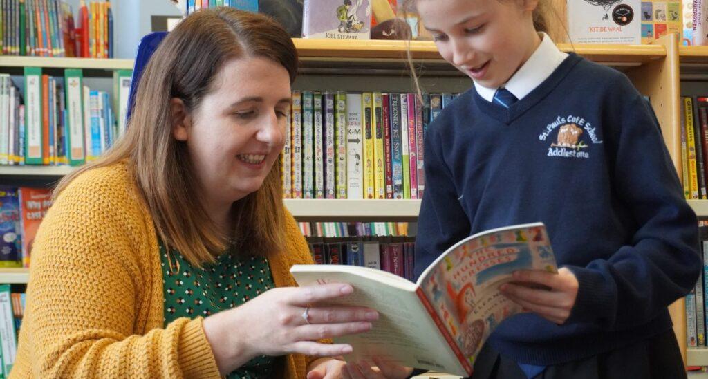 A teacher and child look at a book together